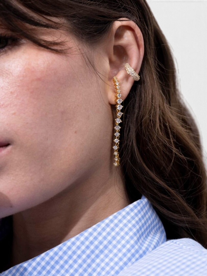 Gouden lange oorstekers met strass op het oor Ellen Beekmans